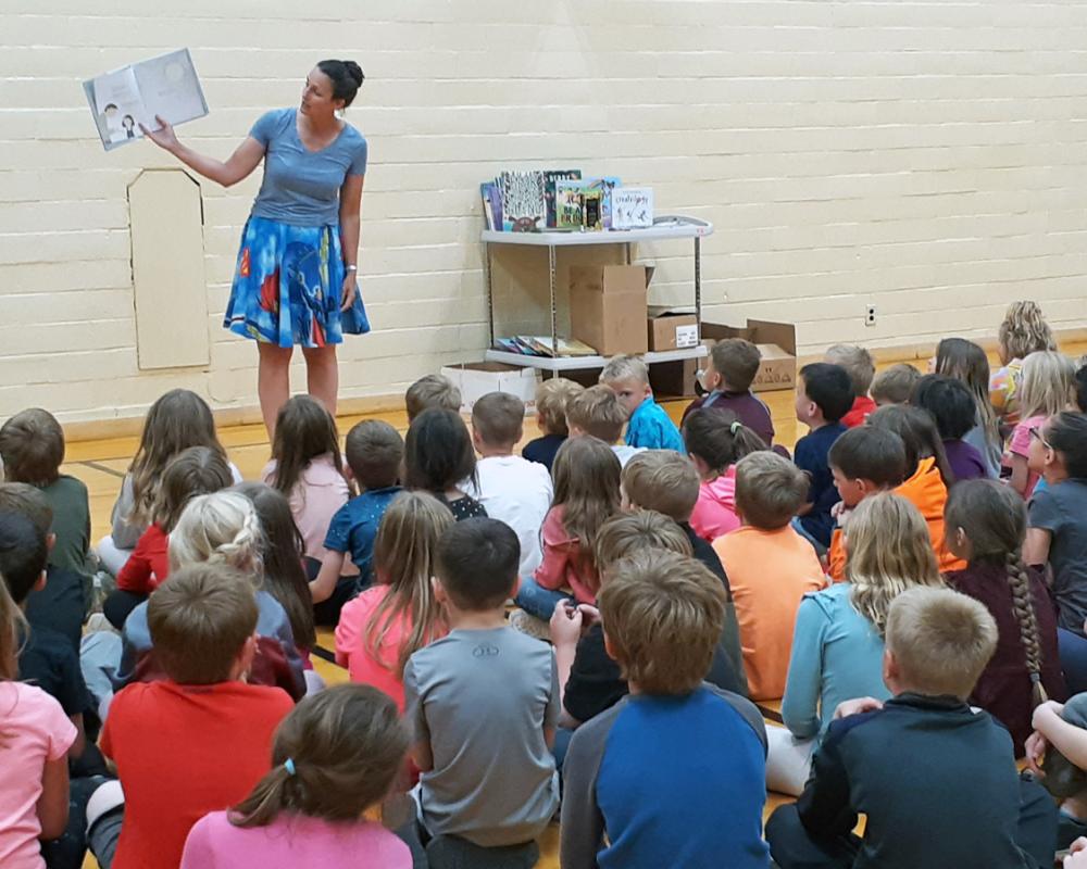 Photo of adult reading to a room full of children