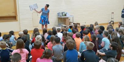 Photo of adult reading to a room full of children